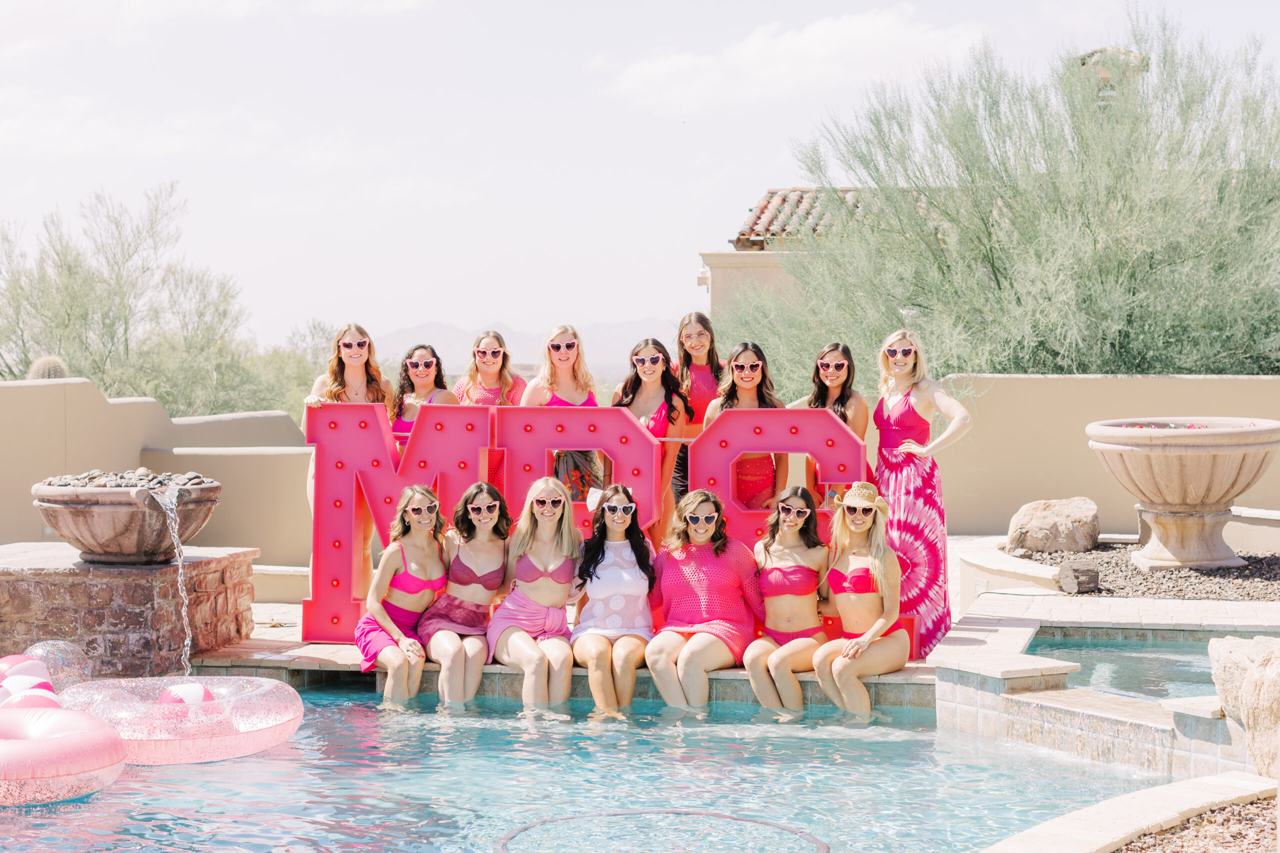 Bachelorette group celebrating in Scottsdale with a Barbie bachelorette theme, champagne squirt guns, pool boys, and giant MRS. marquee letters